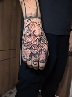 an octopus tattoo on the hand of a man in black pants and a black t - shirt