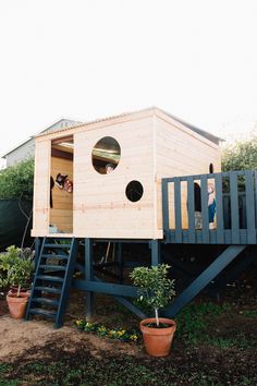 there is a small wooden house with a ladder to the roof and windows on it