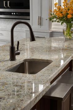 a kitchen with marble counter tops and stainless steel sink faucet in the center