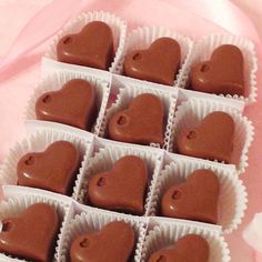 heart shaped chocolates in small white boxes on a pink tableclothed cloth, ready to be eaten