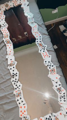 a mirror with playing cards on it sitting on a bed covered in plastic sheeting