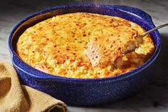 a casserole with meat and cheese in a blue bowl next to a towel