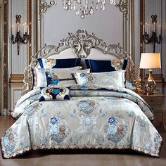 a large bed with blue and white comforters in a fancy style bedroom, along with a chandelier