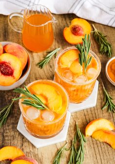 two glasses filled with peaches and ice on top of a wooden table next to sliced peaches