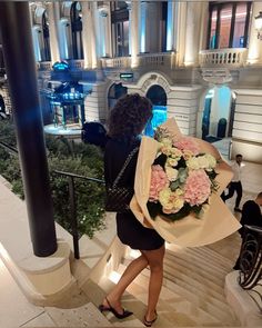 a woman is walking down the stairs with flowers in her hand