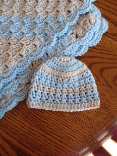 two crocheted hats sitting on top of a wooden table