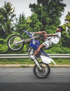 a man riding on the back of a blue and white dirt bike while flying through the air