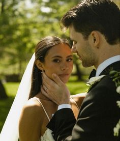 a bride and groom standing together in the grass