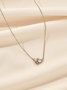 a necklace with three stones hanging from it on a white fabric background, close up