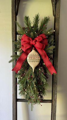 a wooden ladder with a christmas wreath hanging on it's side and a red bow