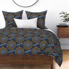 a bed with blue and gold designs on it in a white room next to a clock