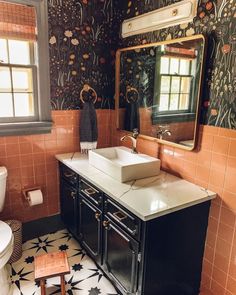 a bathroom with a sink, mirror and tiled flooring in black and white colors