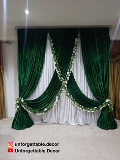 a green and white wedding backdrop with flowers on the top, draped in sheer curtains