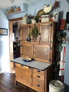 an old fashioned kitchen with wooden cabinets and drawers in the center, along with potted plants