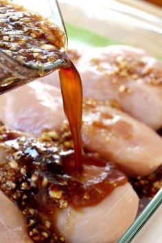 someone pouring sauce on some meat in a bowl