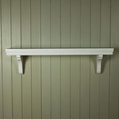 a white shelf on the wall with two hooks