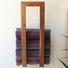 a stack of towels sitting on top of a wooden rack next to a plant and mirror