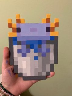 a person holding up a piece of art made out of lego blocks and paper squares