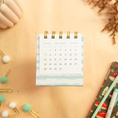 a calendar sitting on top of a desk next to some pens and pencils in front of it