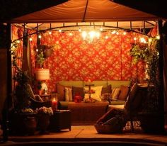 an outdoor living area lit up at night with lights on the ceiling and couches