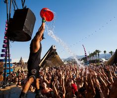 a man holding a red frisbee in front of a large group of people