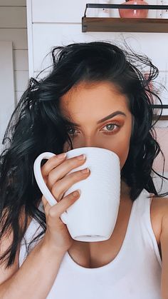 a woman drinking from a white coffee cup