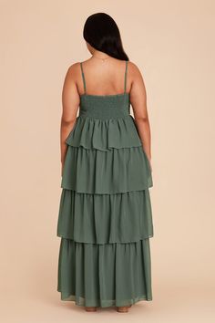 a woman wearing a green dress with tiered layers on the bottom, and back view