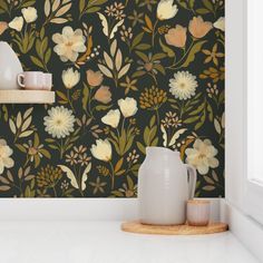 the wallpaper in this kitchen is painted with flowers and leaves, while two vases are on the counter