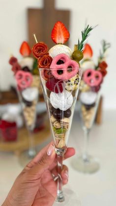 a person holding up a wine glass filled with desserts and pretzel toppings