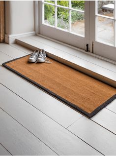 a pair of shoes sitting on the floor next to a door mat in front of a window