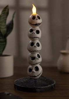 a stack of skulls sitting on top of a table next to a potted plant