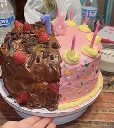 a birthday cake with chocolate frosting and strawberries on the top is being held by a person