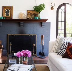 a living room filled with furniture and a fire place in front of a brick wall