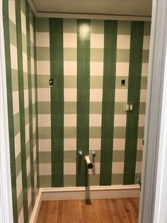 an empty bathroom with green and white striped wallpaper on the walls, toilet paper dispensers in the corner