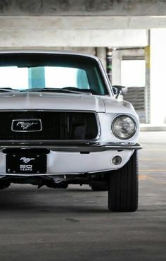 the front end of a white mustang in a parking garage with no one around it