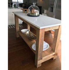 a kitchen island with plates and bowls under a clochet glass dome on top