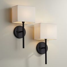 two lamps mounted on the wall next to each other, one with a white shade