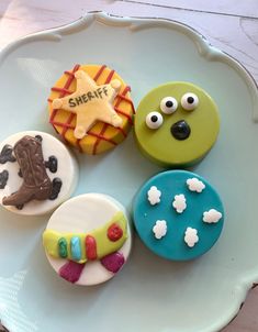 four decorated cupcakes sitting on top of a white plate