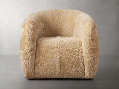 a chair made out of sheep's wool on a grey floor with a wall in the background