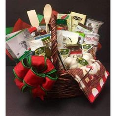 a basket filled with lots of food on top of a black table next to a red bow