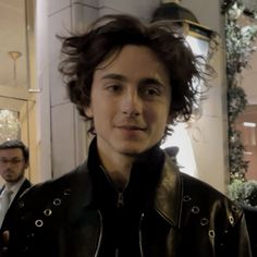 a man in a leather jacket is standing outside