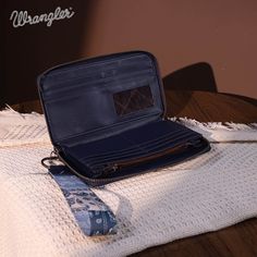 Made of synthetic leather Bandana print on the front with intricate inlay patterns The Wrangler logo on the front Top zipper closure Open compartments, a window ID, and card slots Single removable strap to convert the wallet into a wristlet 8.2"(L) x 1"(W) x 4.8"(H) (Drop: 8.5") Swag Bags, Western Pattern, Swag Bag, Black Purse, Bandana Print, Wristlet Wallet, Black Purses, Contrast Stitch, Western Style