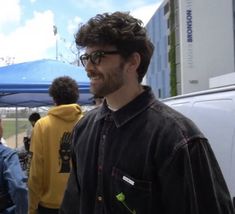 a man standing in front of a group of people wearing glasses and hoodie jackets