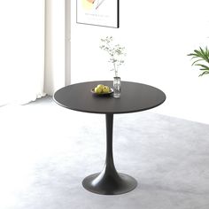 a bowl of fruit sitting on top of a table next to a potted plant