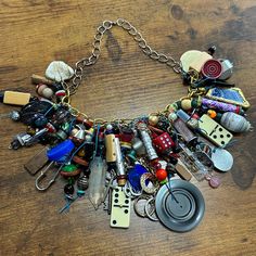 a necklace with lots of different items attached to it on a wooden surface, including buttons and keys