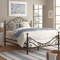 a bedroom with a metal bed frame and white linens on the carpeted floor