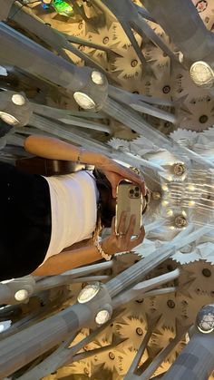 a woman taking a selfie with her cell phone in front of an intricate ceiling