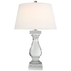 a clear glass table lamp with a white shade on the top and bottom part of it