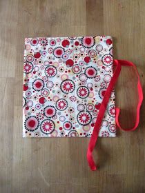 a red and white bag sitting on top of a wooden floor next to a pair of scissors