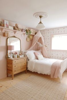 a bedroom decorated in pink and white with a bed, dresser, mirror and rug